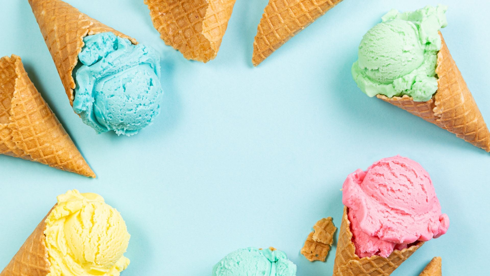 An overhead shot of a bright blue background. Along the edges of the image are waffle cones with bright scoops of ice cream.